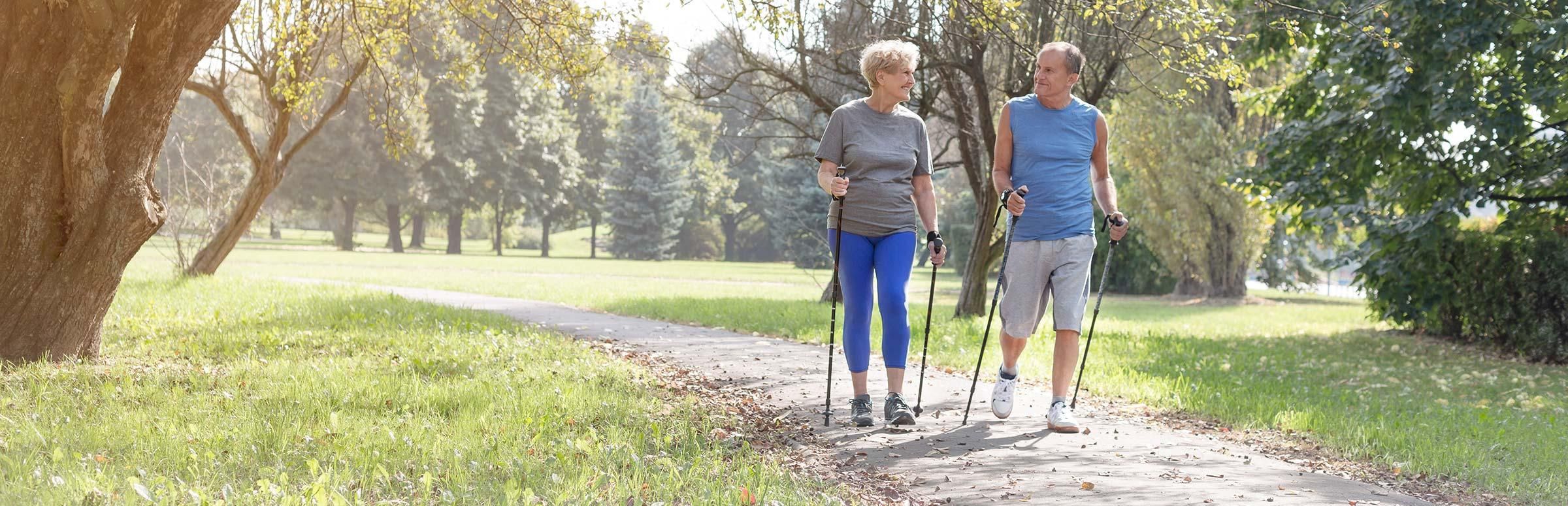 Mann und Frau im höheren Alter laufen durch einen Park.