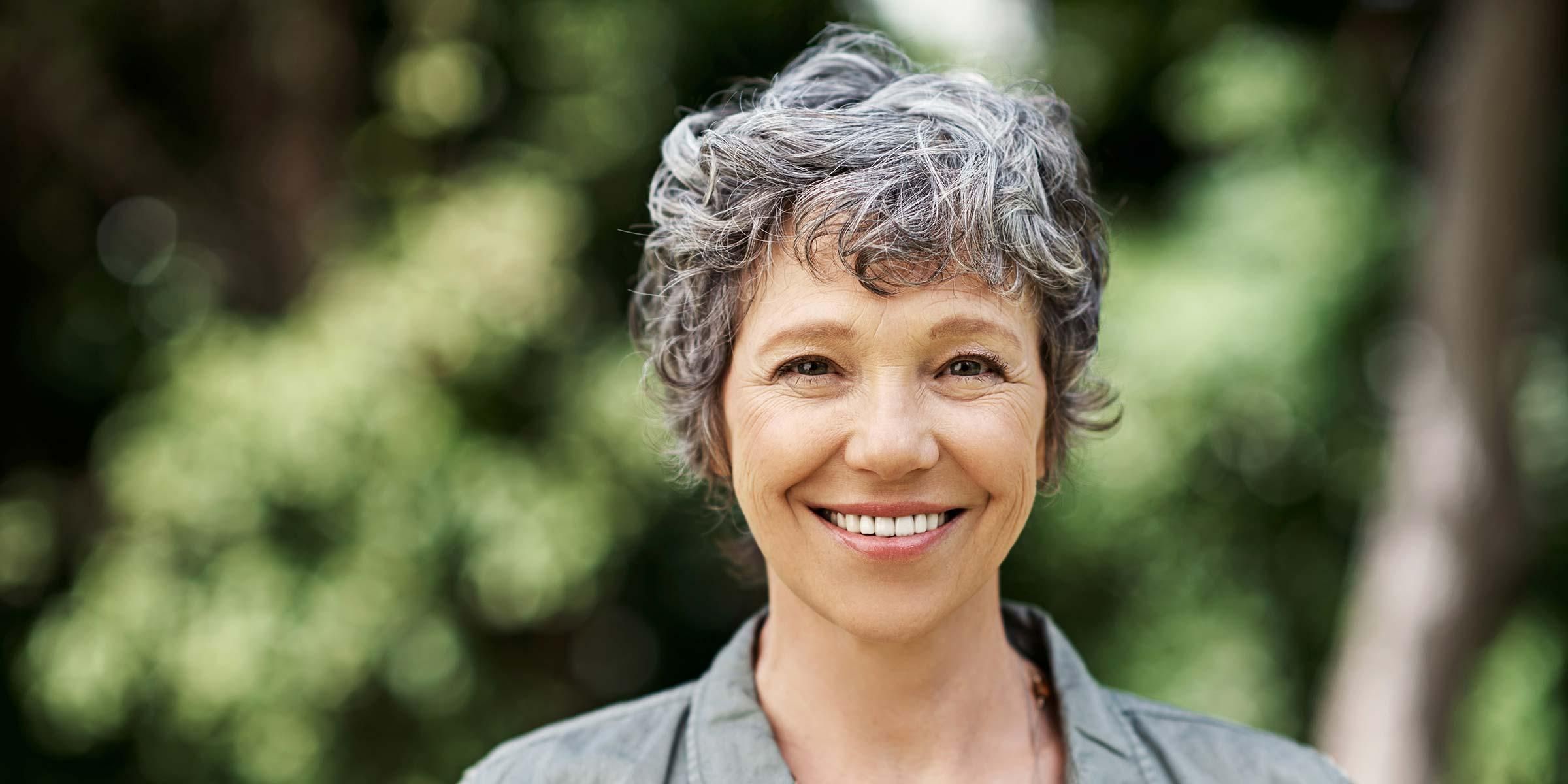 Frau mit grauen Haaren lächelt in die Kamera