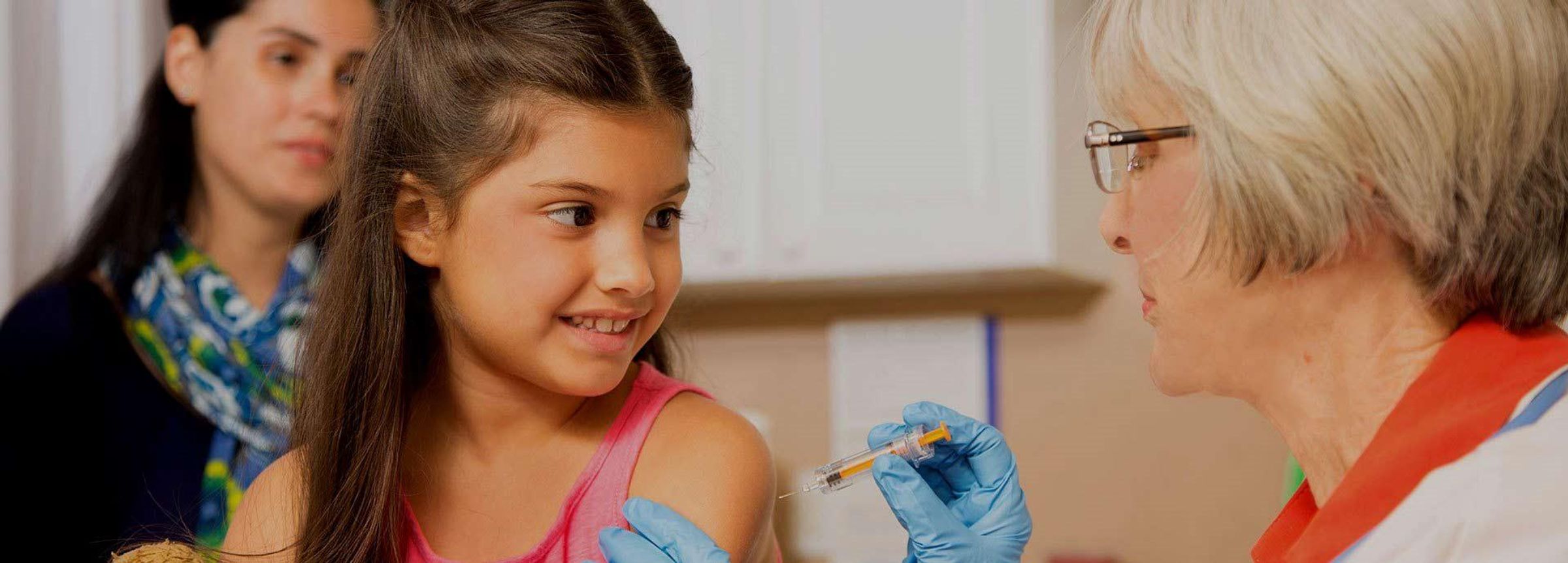 Mutter mit ihrer Tochter beim Arzt, die gerade geimpft wird