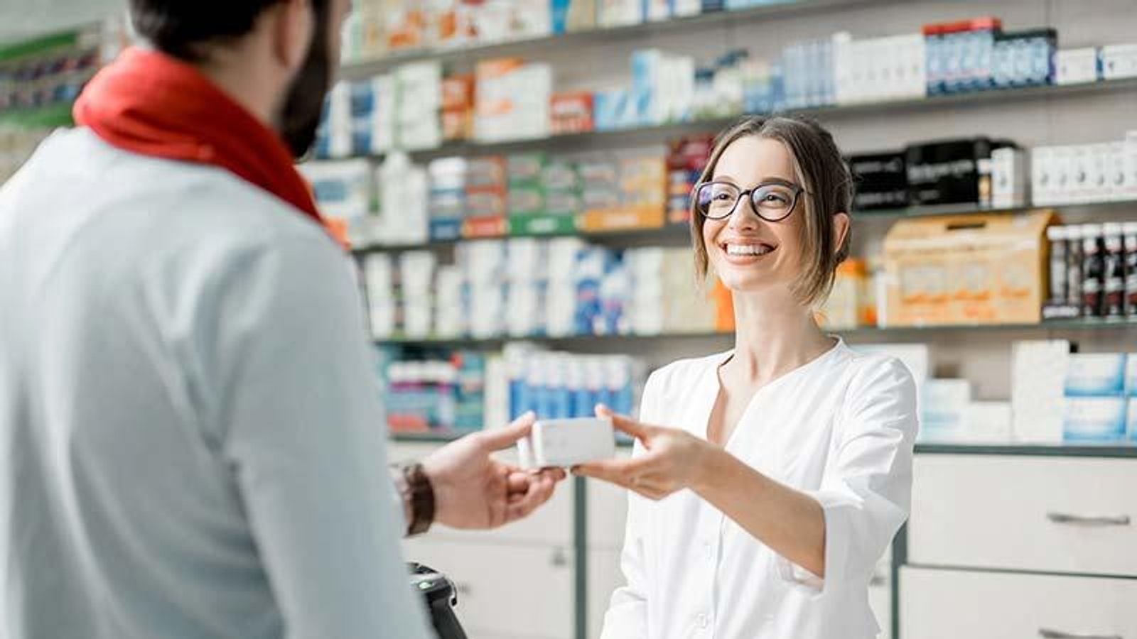 Apothekerin überreicht einem Patienten ein Arzneimittel