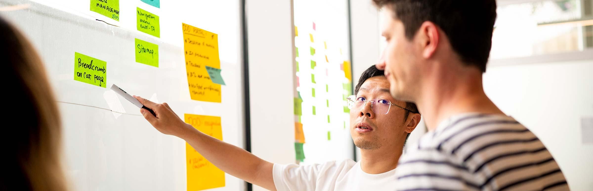 Zwei Männer stehen vor einer Projektwand